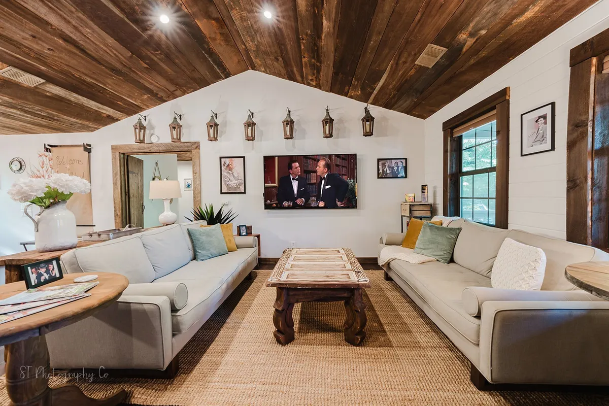 A cozy living room arrangement featuring comfortable sofas, coffee table, a streaming-enabled TV, and decorative wall lanterns. The setup is ideal for socializing, TV marathons, or simply unwinding.